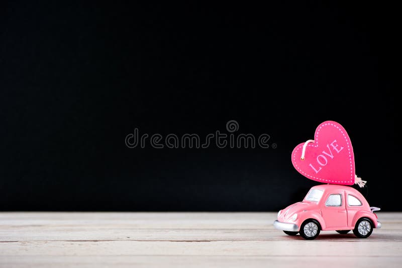 Little beetle pink car carries a heart with love in blank background for text, Valentine`s Day concept, Mother`s Day concept, macro shot.