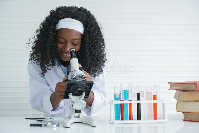 Little Black girl smile with a microscope various colorful flasks test tube and text books