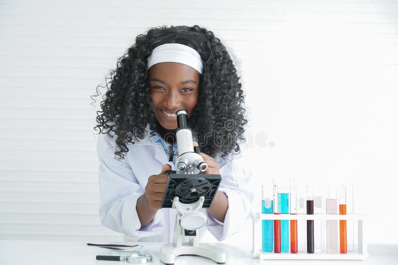 Little Black girl smile with a microscope various colorful flasks and test tube