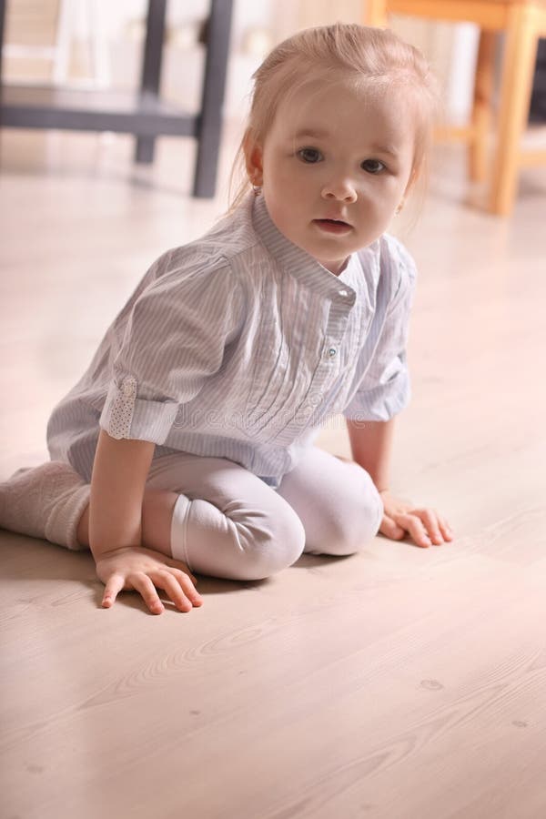 Little blond girl in striped shirt sitting on wooden floor royalty free stock photo Little blond girl in striped shirt sitting on wooden floor royalty free stock photo