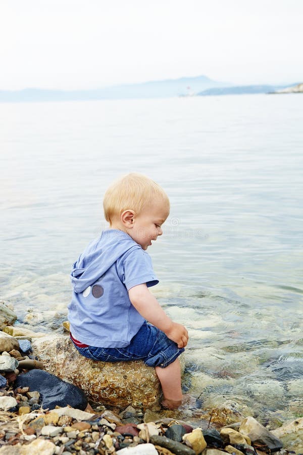 Little blond one year old boy sitting on a rock royalty free stock image Little blond one year old boy sitting on a rock royalty free stock image