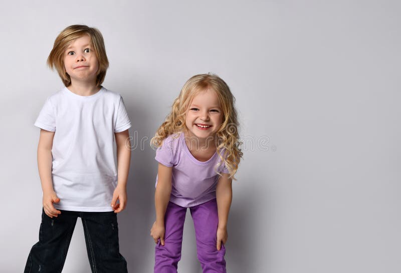 Little blonde girl in purple t-shirt and pants and boy in black and white casual clothes. They smiling, posing isolated on white stock images Little blonde girl in purple t-shirt and pants and boy in black and white casual clothes. They smiling, posing isolated on white stock images