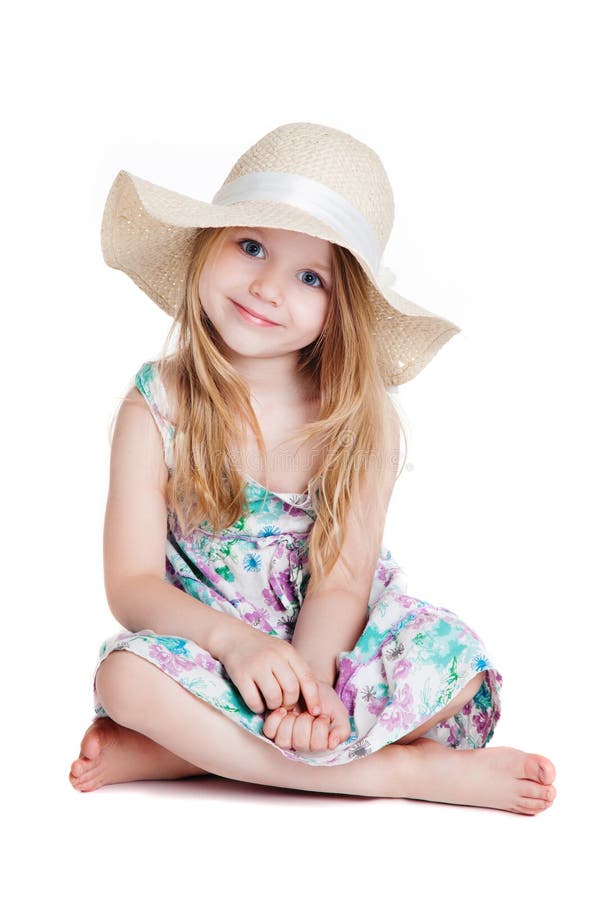 Little blonde girl wearing hat and dress sitting on the floor