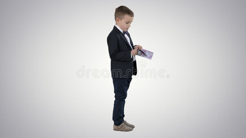 Little boy in black suit counts money on gradient background.