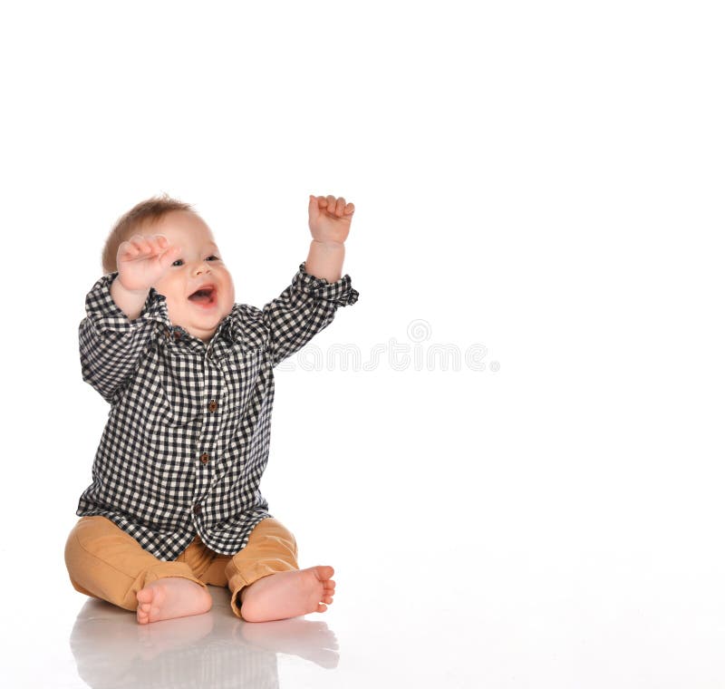 Little boy pulls his hands up in the studio on a white background. Little boy in a black and white plaid shirt and beige pants raises his hands up and smiles stock photos Little boy pulls his hands up in the studio on a white background. Little boy in a black and white plaid shirt and beige pants raises his hands up and smiles stock photos