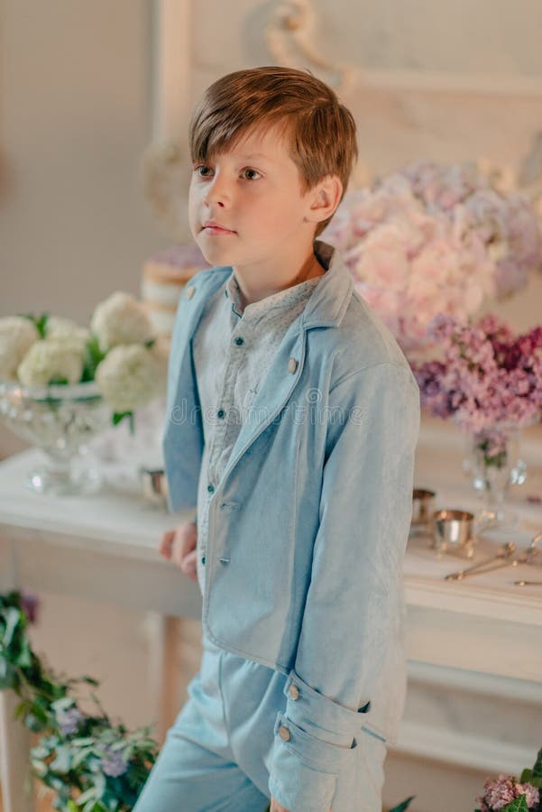 The Little Boy in the Blue Suit in the Studio with Flowers Stock Photo
