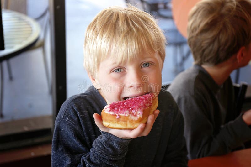Little Boy Child Eating Forsted Donut at Bakery with his Family stock image Little Boy Child Eating Forsted Donut at Bakery with his Family stock image