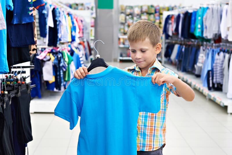 Little boy chooses shirt in clothing store