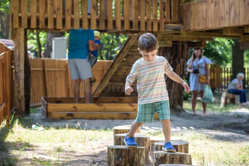 Little boy climbing on a wooden playground in rope park. Kid play outdoors warm sunny summer day royalty free stock photos Little boy climbing on a wooden playground in rope park. Kid play outdoors warm sunny summer day royalty free stock photos