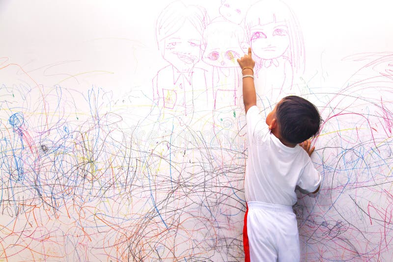 Little boy drawing happy family on the wall