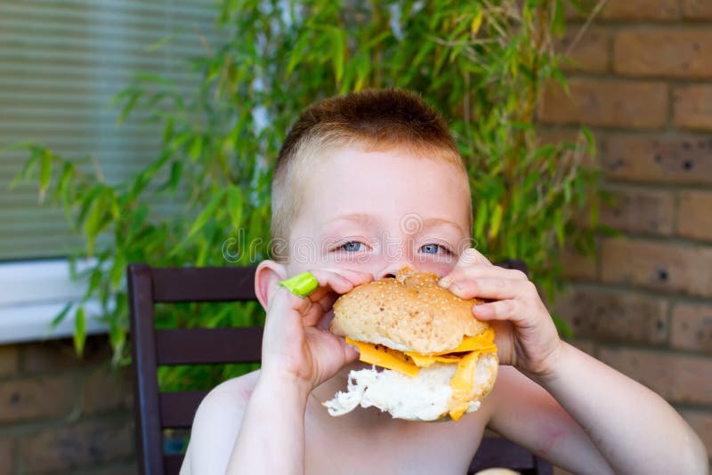 Little boy eating a huge burger