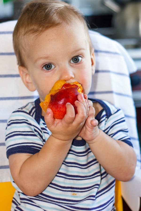 Little boy eating a peach. 