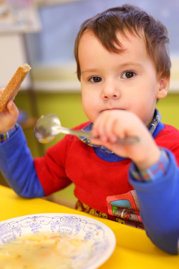 Little boy eats in kindergarten stock photos Little boy eats in kindergarten stock photos