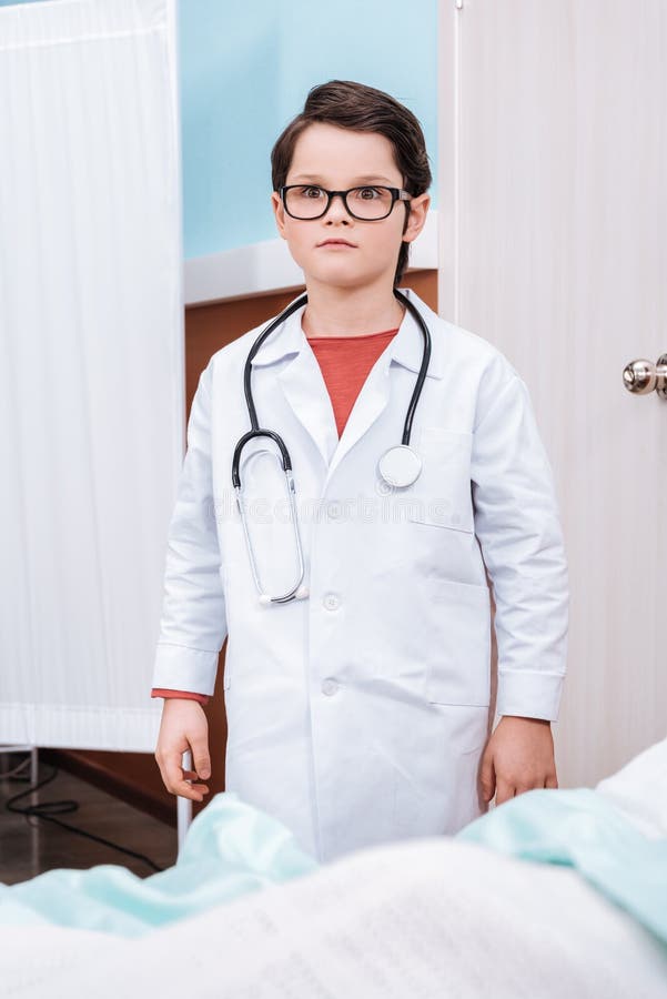 Little boy in eyeglasses with stethoscope pretending to be a doctor