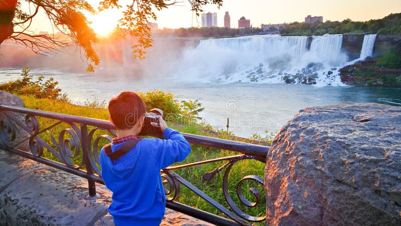 A little boy is filming the morning sun of Niagara Falls.