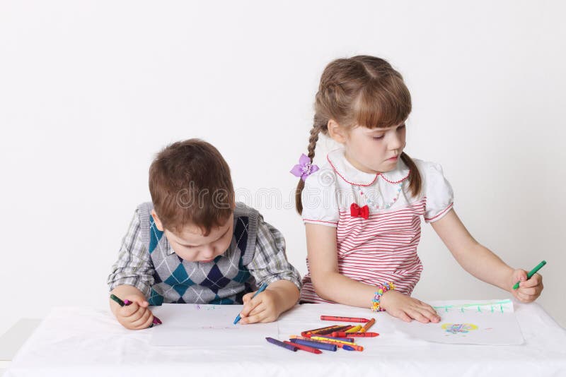 Little boy and girl draw with crayons sitting