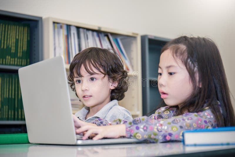 Little boy and girl playing computer games. Small boy and girl tying with laptop stock image Little boy and girl playing computer games. Small boy and girl tying with laptop stock image