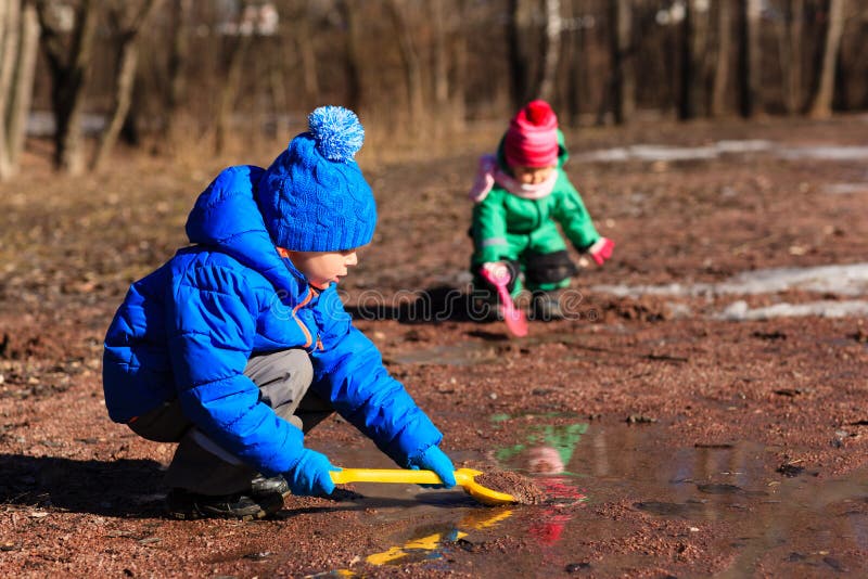 Little boy and girl playing with water in spring