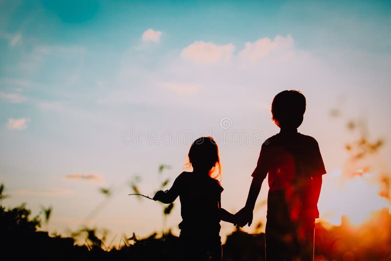 Little boy and girl silhouettes holding hands at sunset