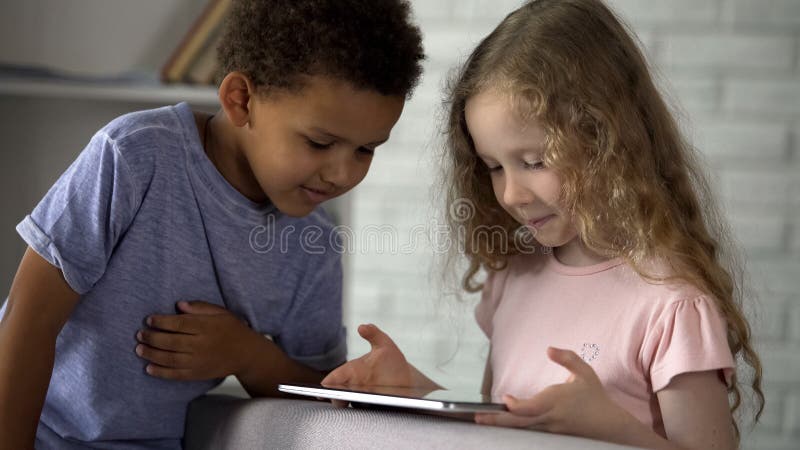 Little boy and girl watching movie on tablet at kindergarten, early development