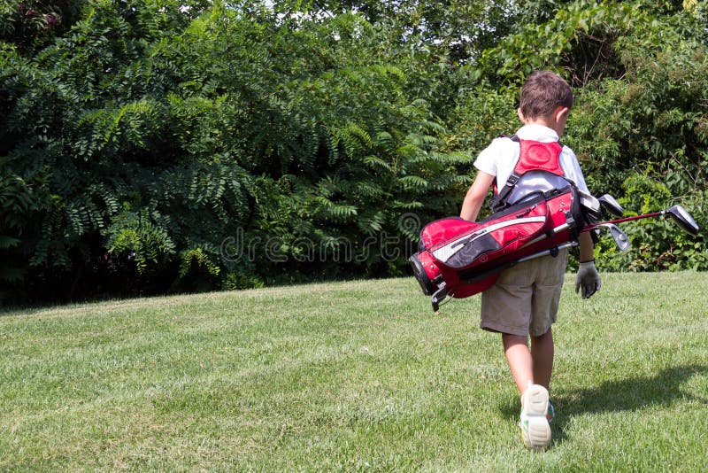Little Boy Golfer Walking with His Golf Bag on the Fairway Stock Photo