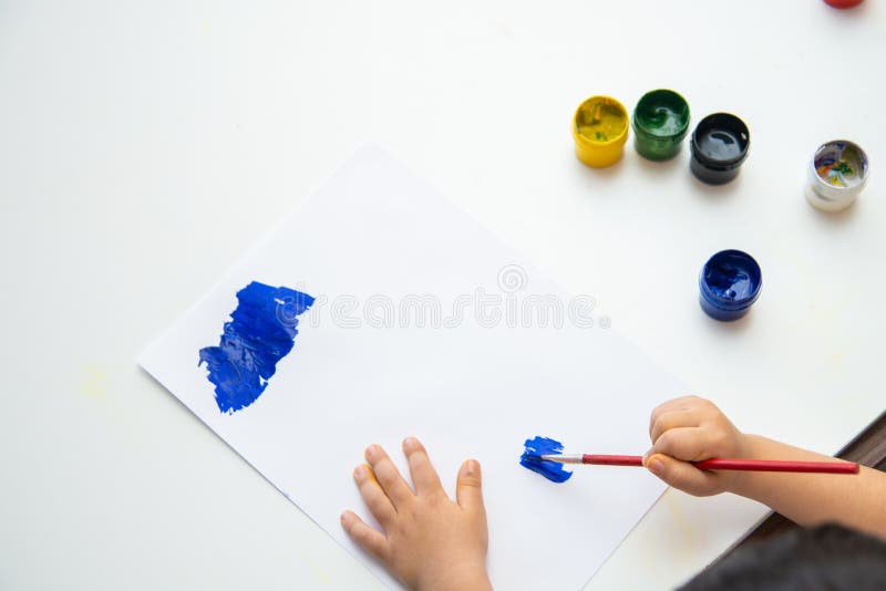 Little boy hand draws on paper. Cute Child boy is sitting and painting. Stay home royalty free stock photos Little boy hand draws on paper. Cute Child boy is sitting and painting. Stay home royalty free stock photos