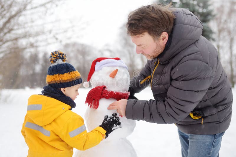 Little boy with his father building snowman in snowy park. Active outdoors leisure with children in winter royalty free stock image Little boy with his father building snowman in snowy park. Active outdoors leisure with children in winter royalty free stock image