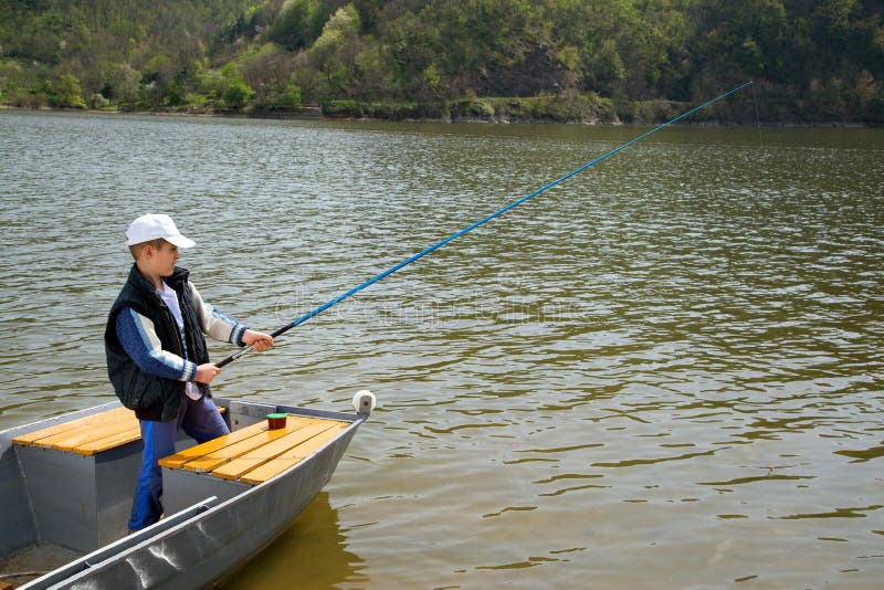 Little Boy Holding A Fishing Rod And Fishing From Wooden Boat On The Lake