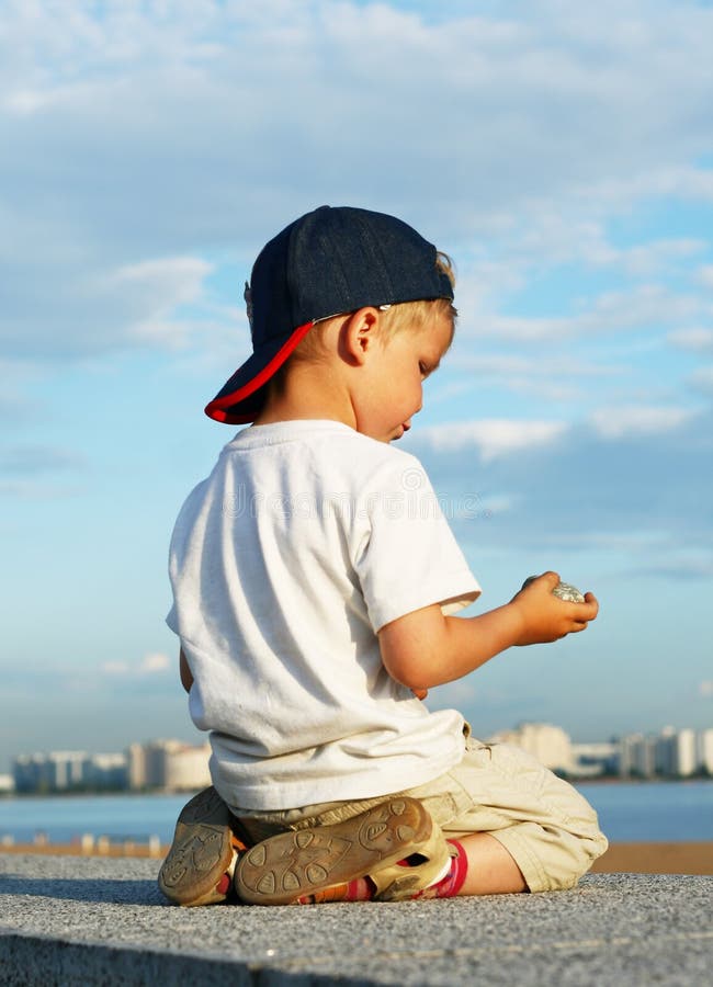 Little boy kneels on the quay