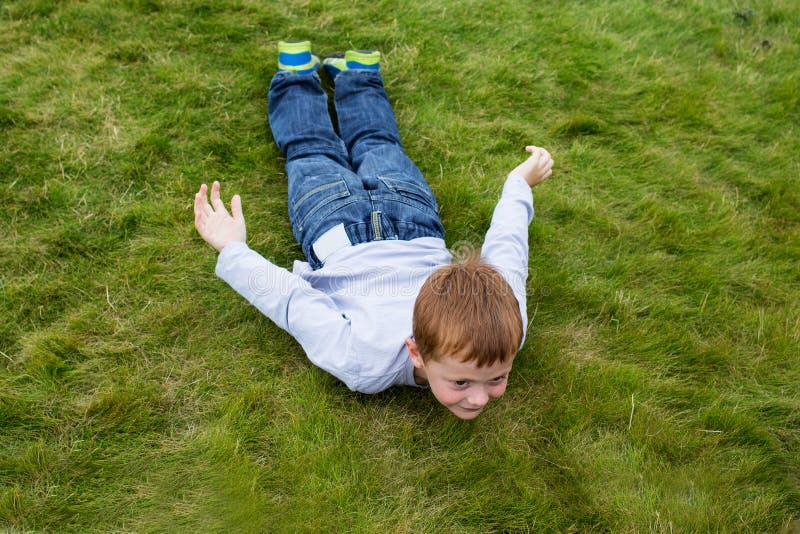 Little Boy Laying on the Grass in Sliding Pose Stock Photo - Image of