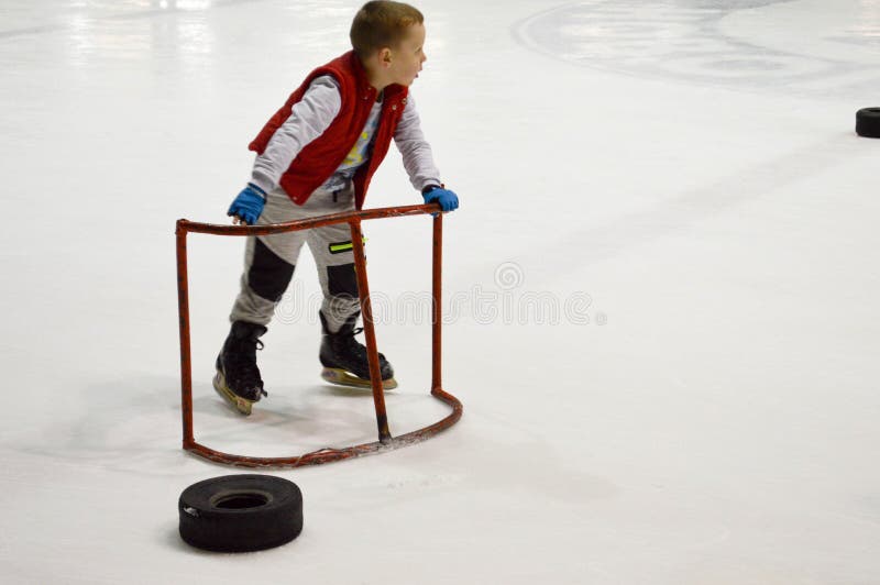 Little boy learns to skate with the help of special supporting gates on the ice hockey arena, April 14, 2018, Belarus stock photo Little boy learns to skate with the help of special supporting gates on the ice hockey arena, April 14, 2018, Belarus stock photo