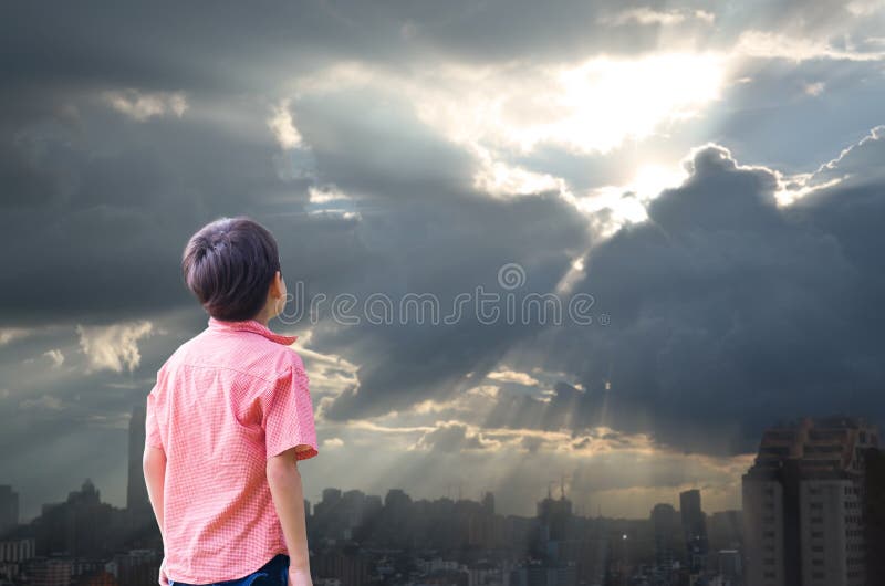 Little boy look up high in the sky sun with cloudy