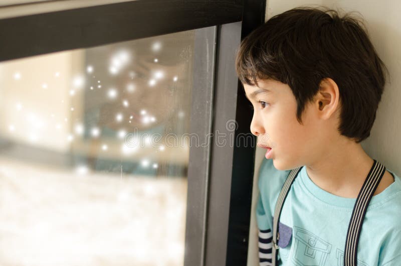 Little boy looking at snow outside of window