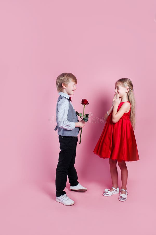 Little boy in love giving cute girl red rose , Valentines day