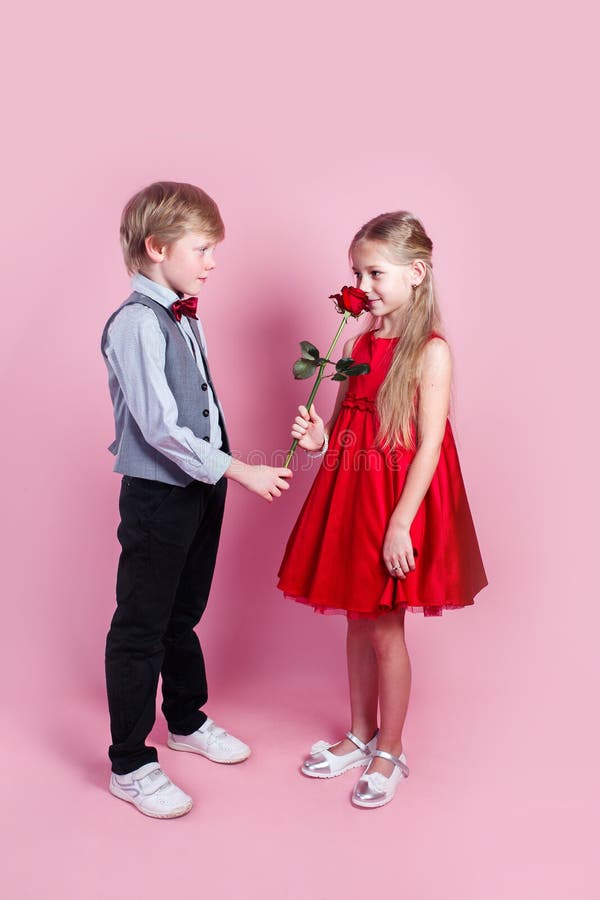 Little boy in love giving cute girl red rose , Valentines day