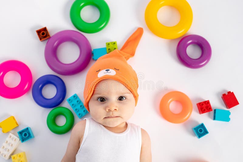 A Little Boy Lying on a White Background among the Toys of the Ring