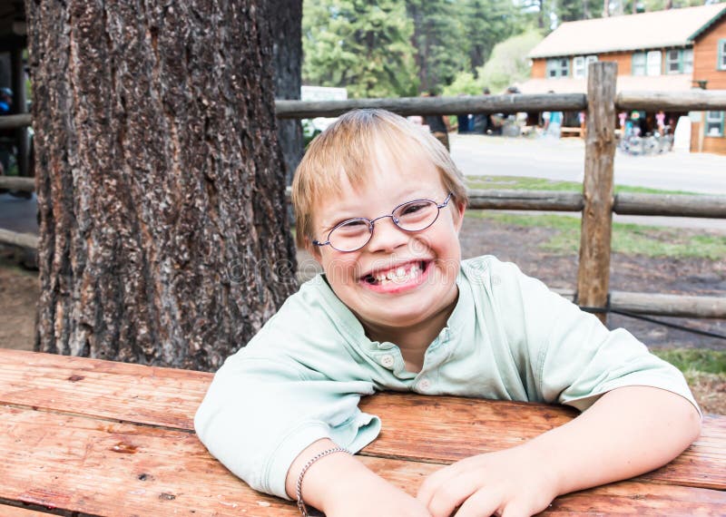 Little Boy med Besegra-syndrom sammanträde på tabellen arkivfoton Little Boy med Besegra-syndrom sammanträde på tabellen arkivfoton