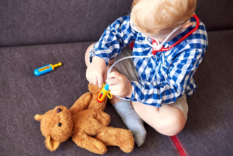 Little boy playing doctor with toy tools and teddy bear