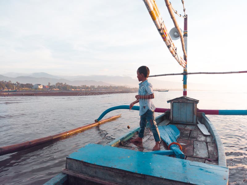 Little boy with fishing rod sitting on boat stock photo