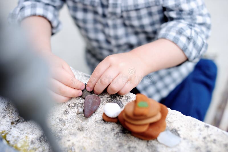 Little boy playing with little stones outdoors