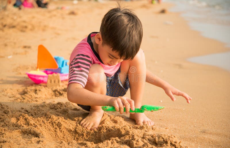 Little boy playing sand on the beach summer