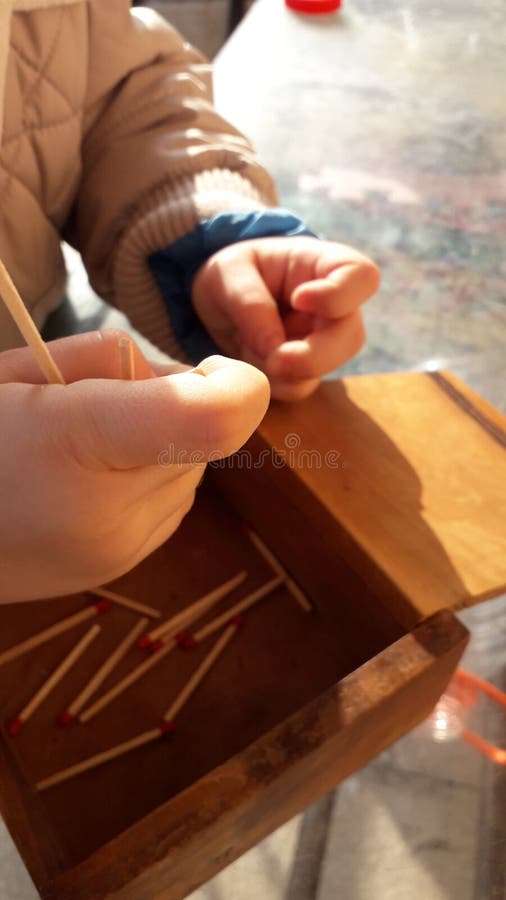 A little boy plays with wooden matches, matchsticks and old wood box