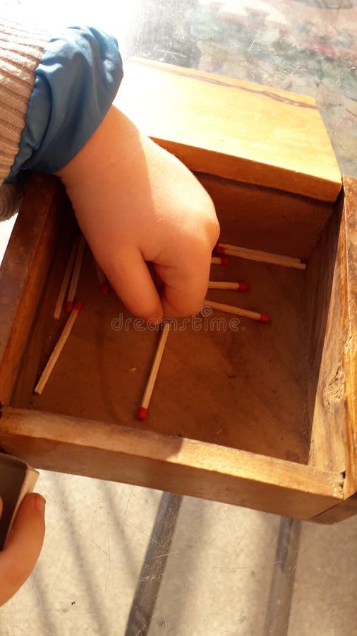 A little boy plays with wooden matches, matchsticks and old wood box