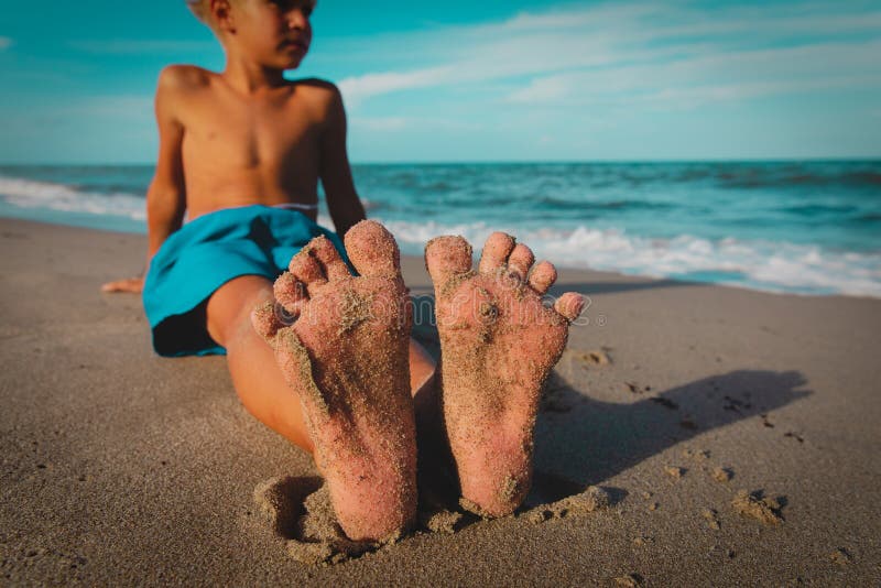 Little boy relax at summer beach, focus on feet. 