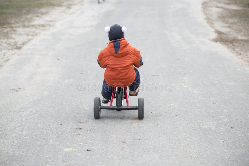 The little boy is riding a tricycle.