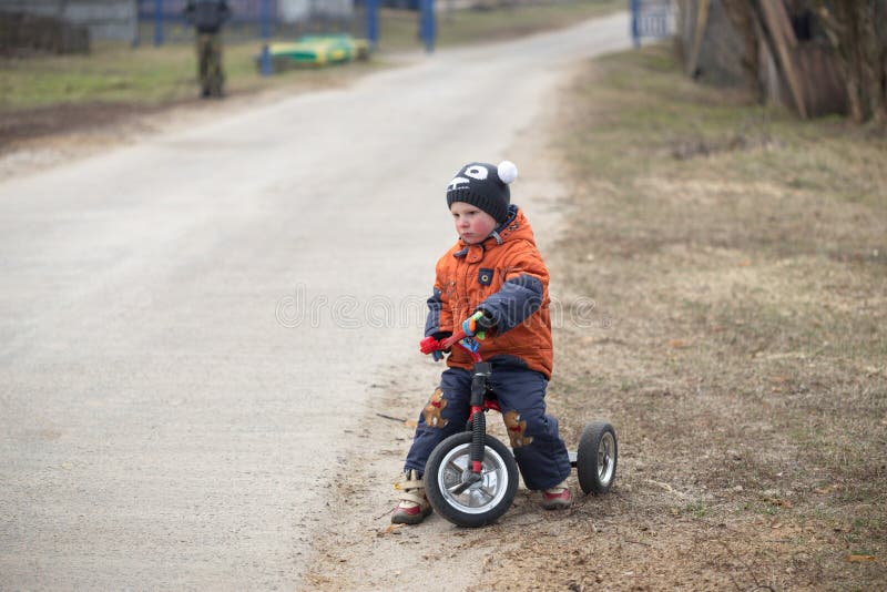 The little boy is riding a tricycle.