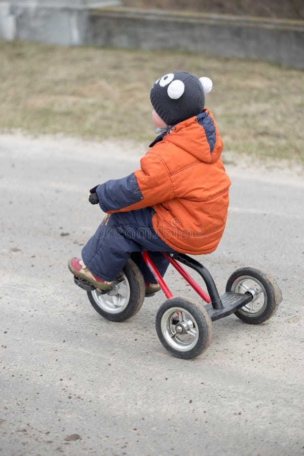 The little boy is riding a tricycle.