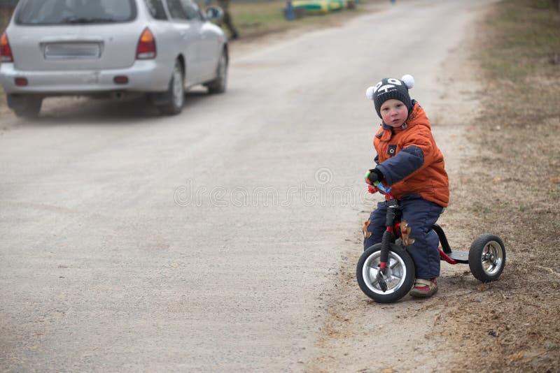 The little boy is riding a tricycle.