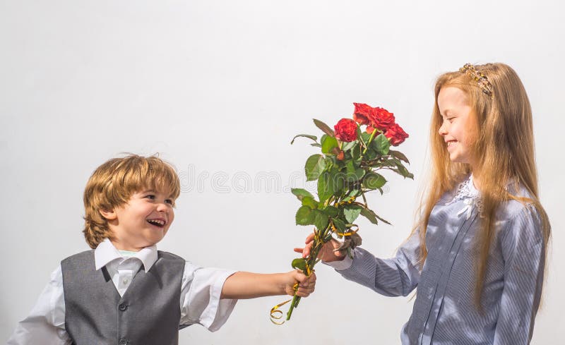 Little Boy with a rose for his teen girlfriend, romantic children, isolated on white background. Kids couple in love.