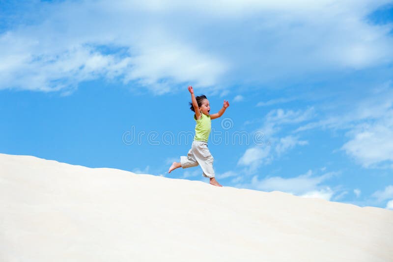 Little boy running on sand dune